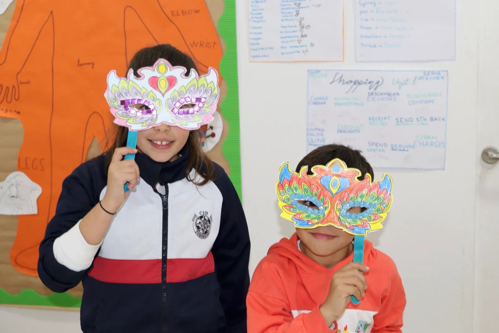 Dos alumnos enseñando las máscaras de carnaval que hicieron en clase